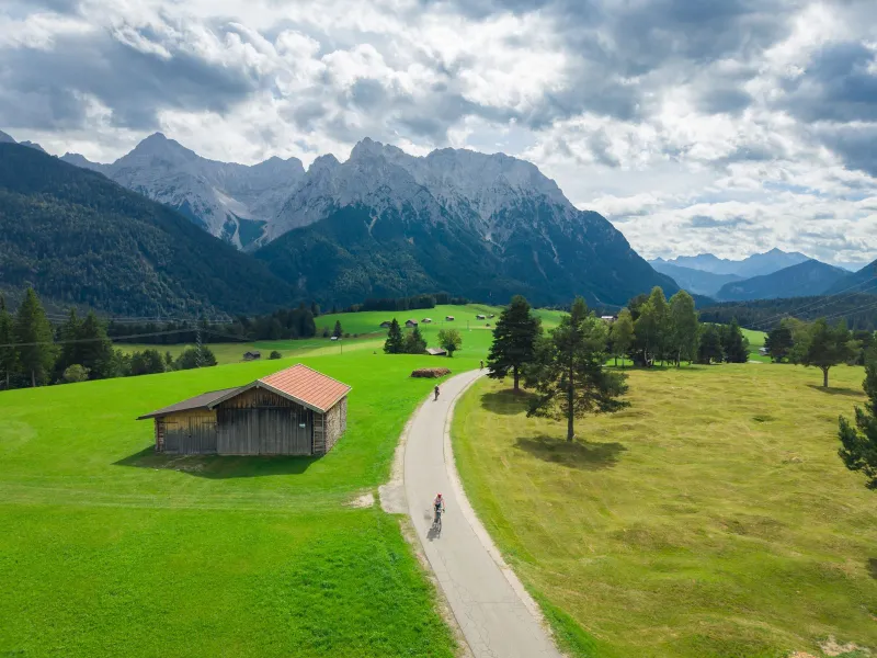 A rider on a narrow road through green meadows under the Wetterstein mountains