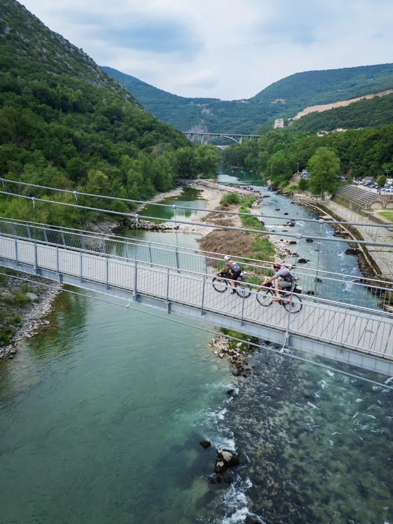 A rider crossing a footbridge over the Soča, seen from above
